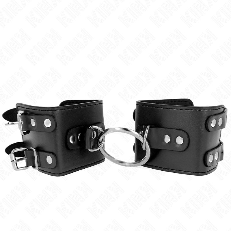 Muñequera fija ajustable KINK con anilla y tachuelas negras, tamaño 17-22 cm x 6.5 cm, para restricción y bondage.