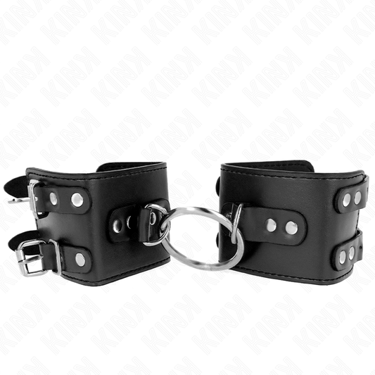 Muñequera fija ajustable KINK con anilla y tachuelas negras, tamaño 17-22 cm x 6.5 cm, para restricción y bondage.